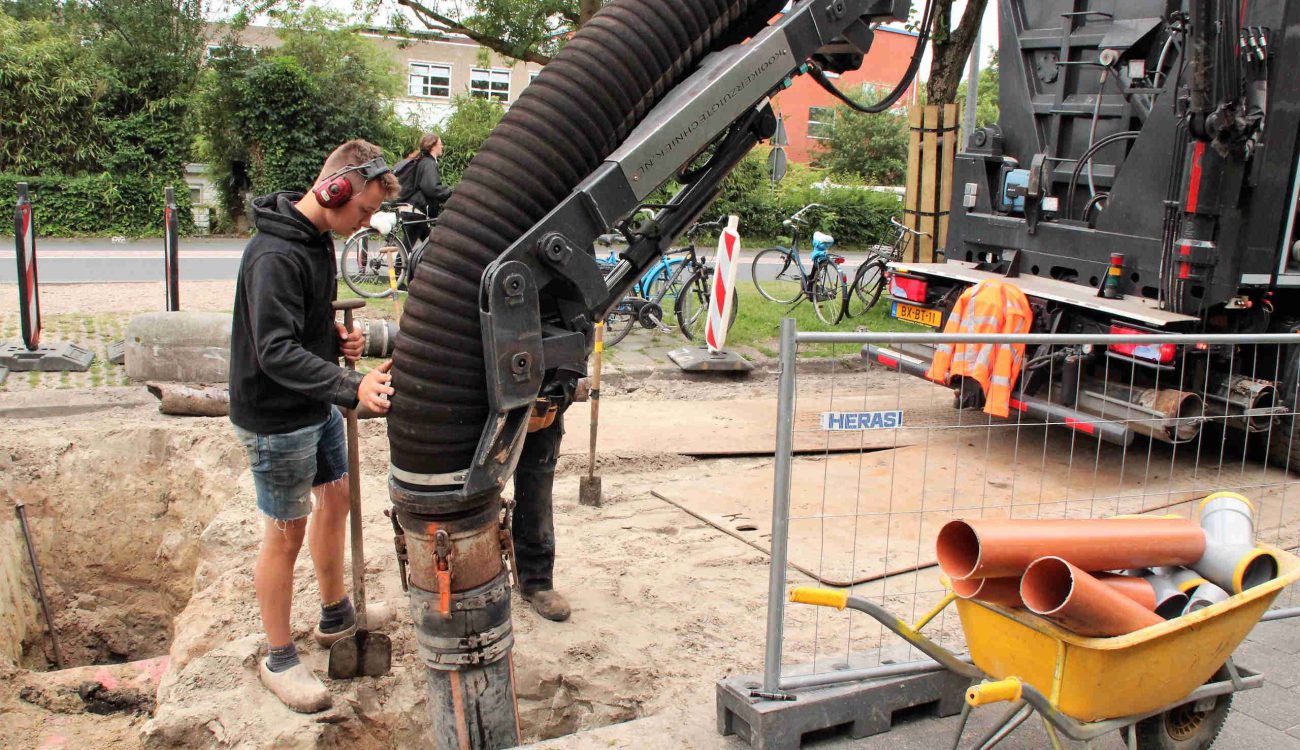 Wegzuigen zand voor vrijmaken riool Groningen